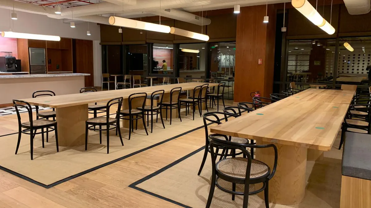 Completed office breakout area with long timber tables, bentwood chairs and a pantry counter, ready for occupation