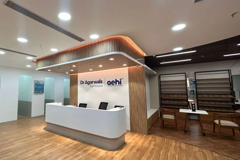 Reception desk with a timber-slatted canopy and optical display shelving at the Dr Agarwal Eye Hospital expansion in Vashi