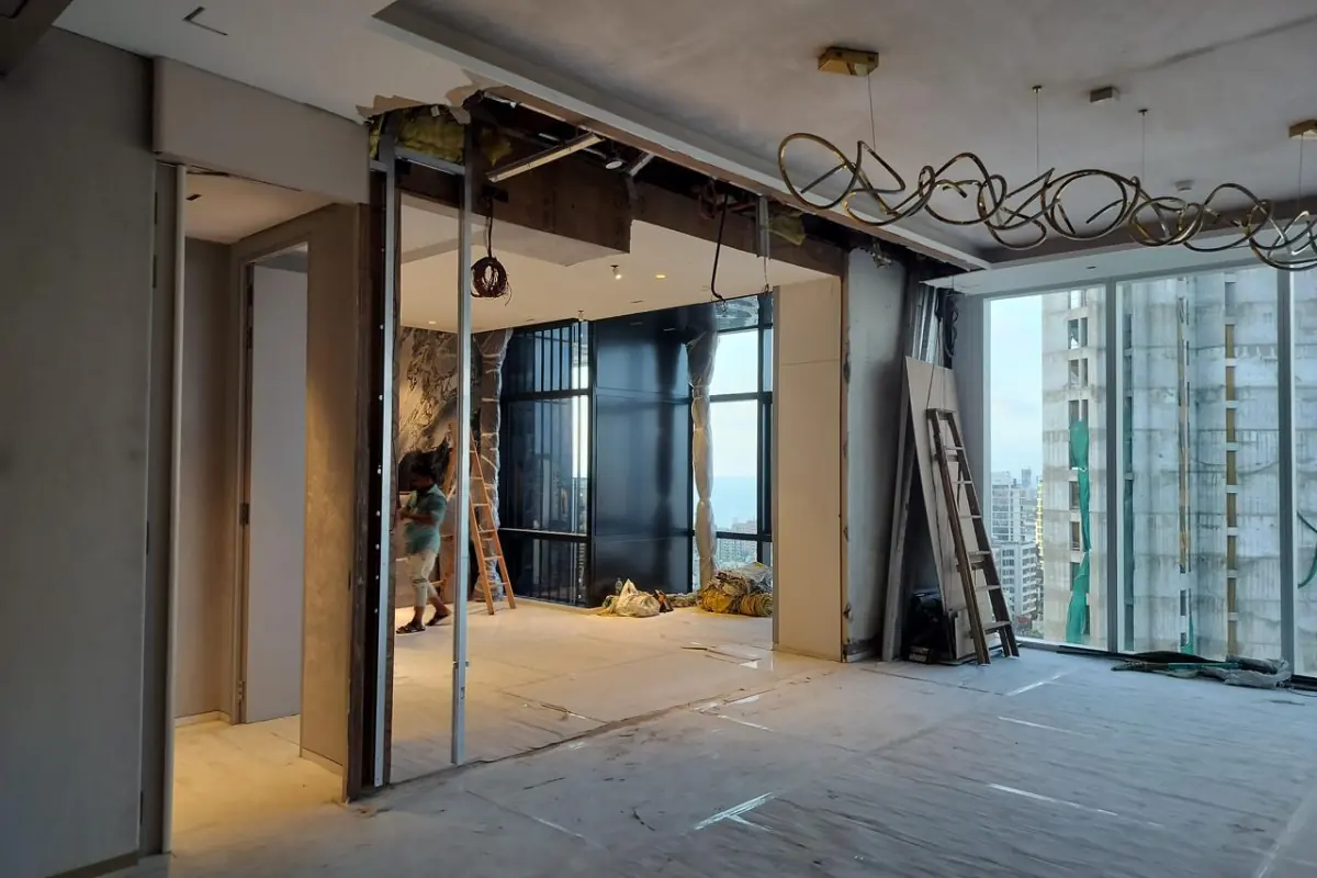 High-rise flat mid-renovation, with the false ceiling opened up, new door frames in place and the floor covered for protection